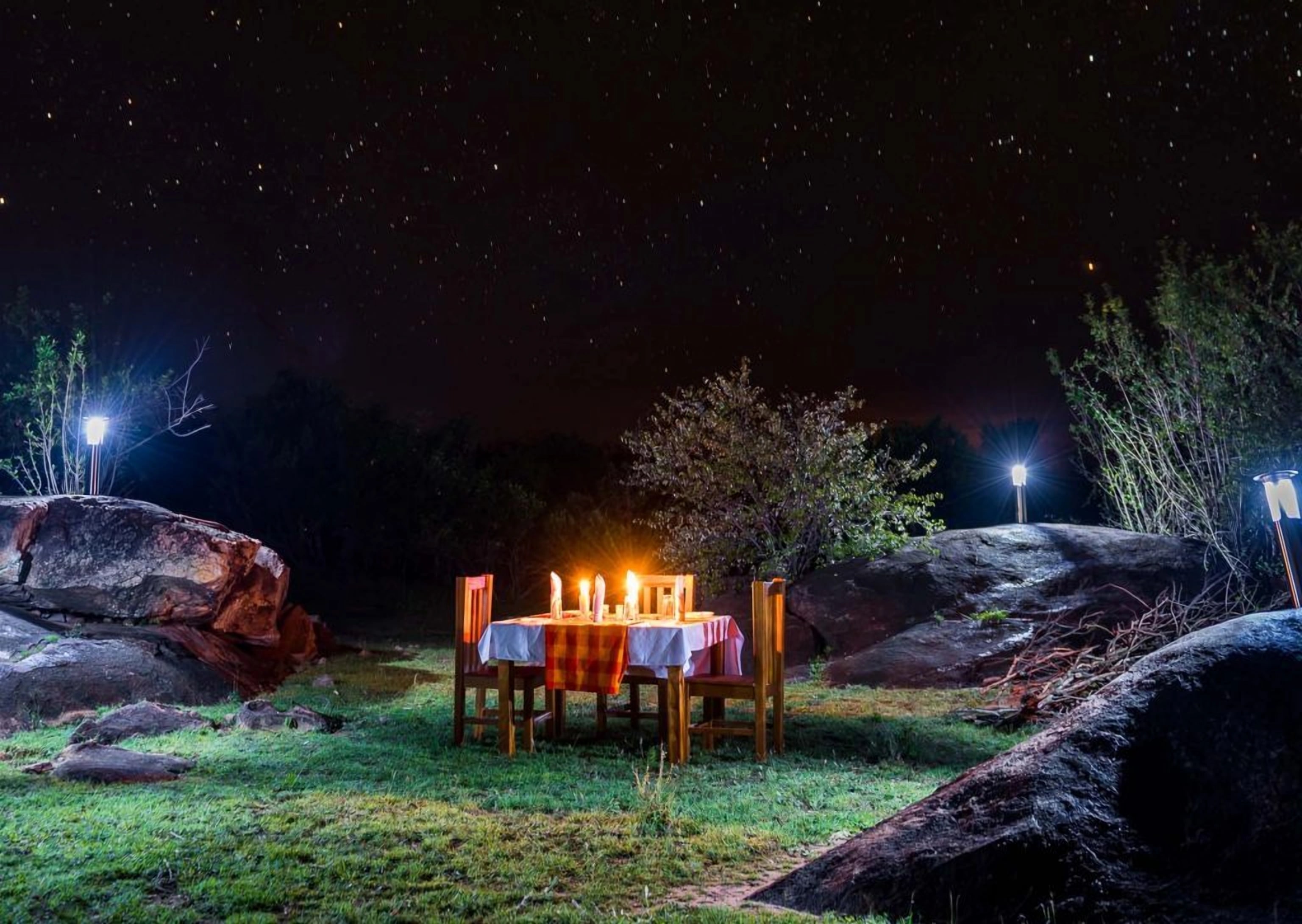 Candlelit table set for two in the bush at night